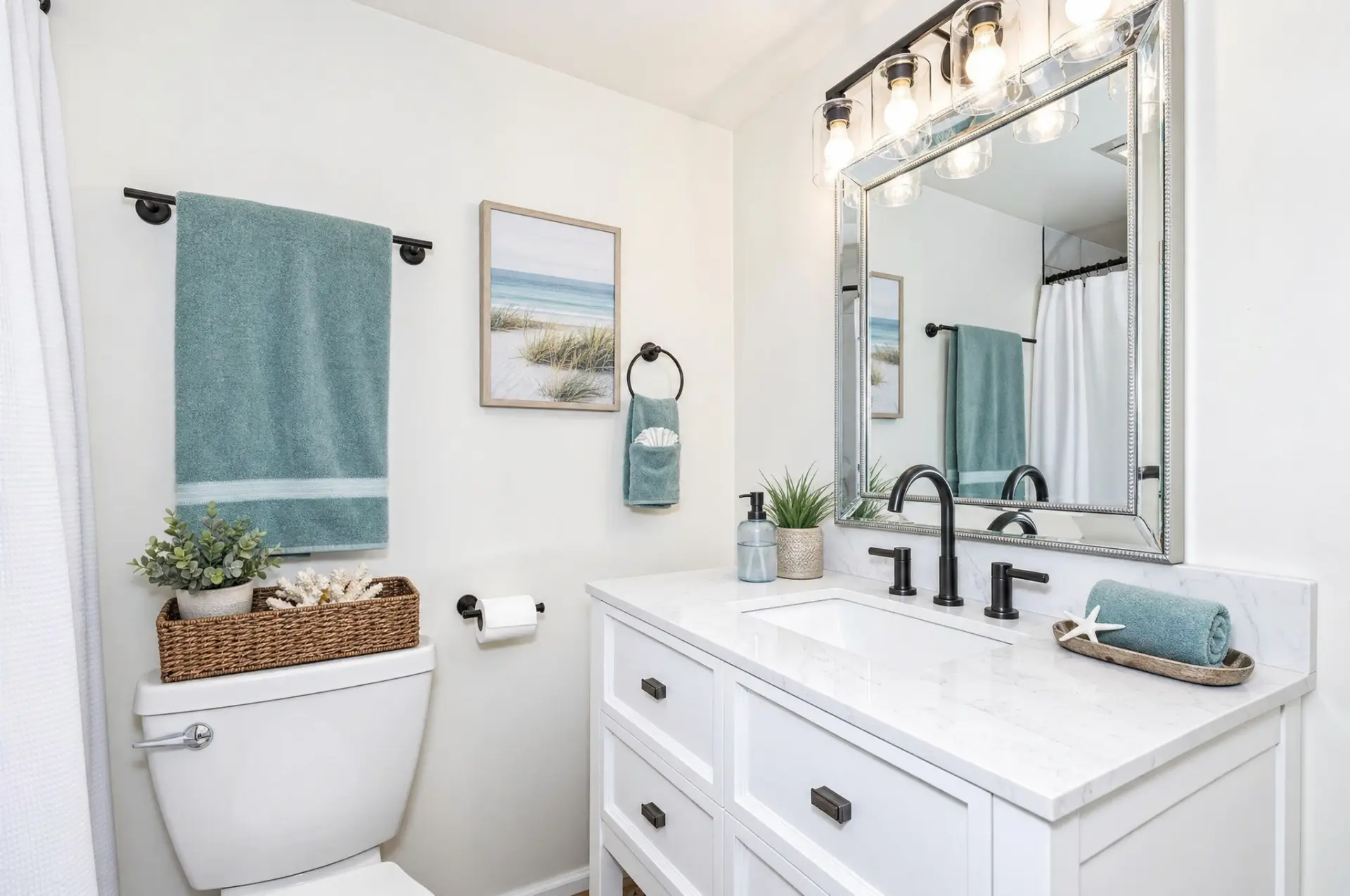 Fresh white bathroom with a wide vanity, black fixtures, blue towels, and framed mirror